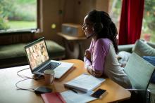 young African-American woman engaging with others through a laptop