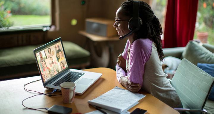 young African-American woman engaging with others through a laptop